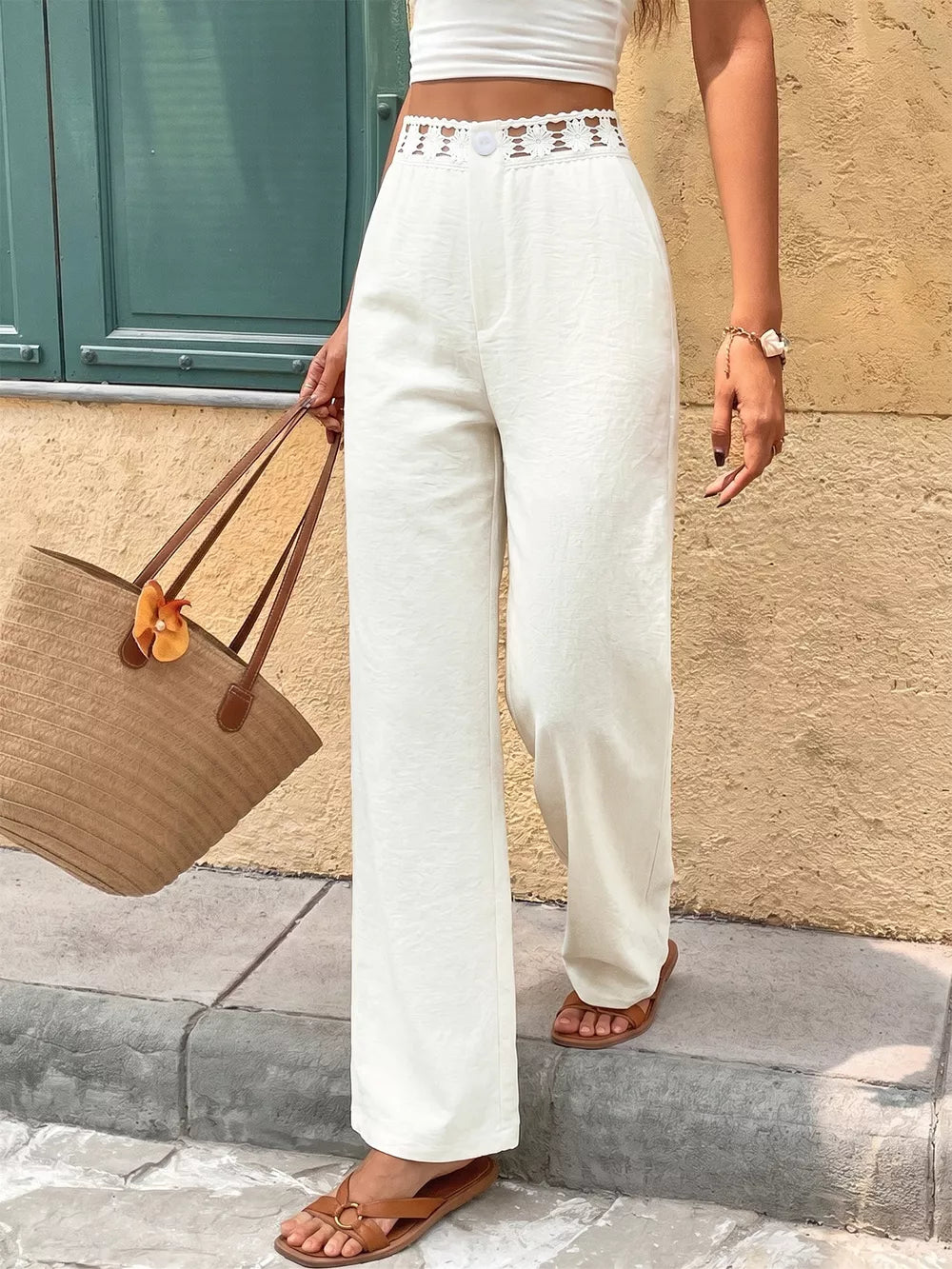White wide-leg pants with crochet waistband detail and button closure.