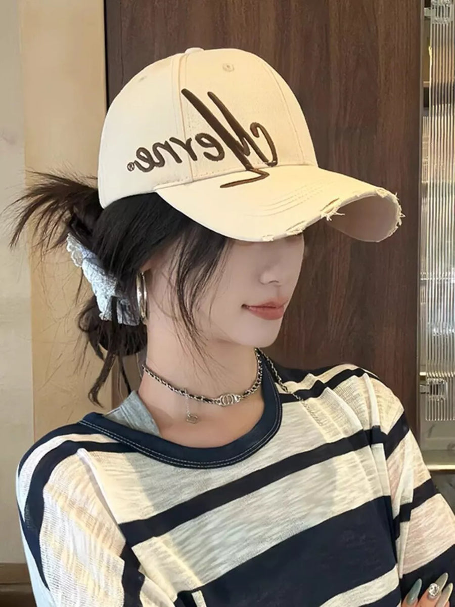 Ivory cotton baseball cap with embroidered script and distressed brim.