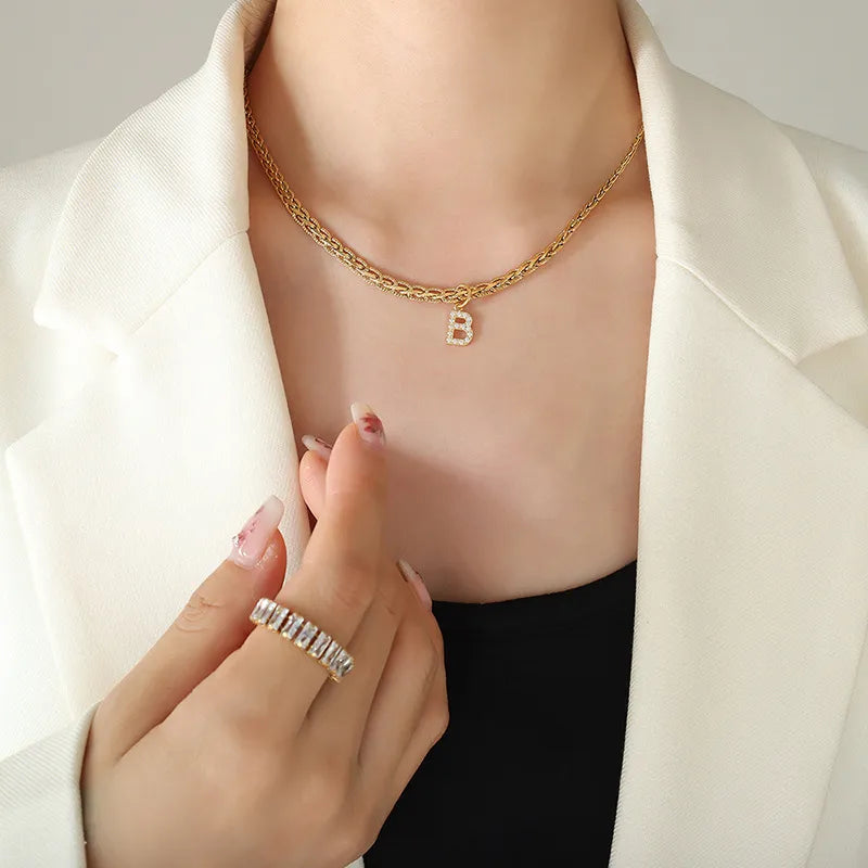 Gold chain necklace with a pave B initial pendant and a baguette ring.