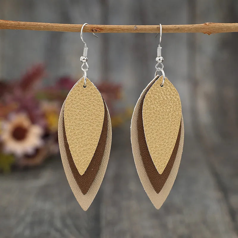 Layered tan leatherette statement earrings with brown and beige accents.