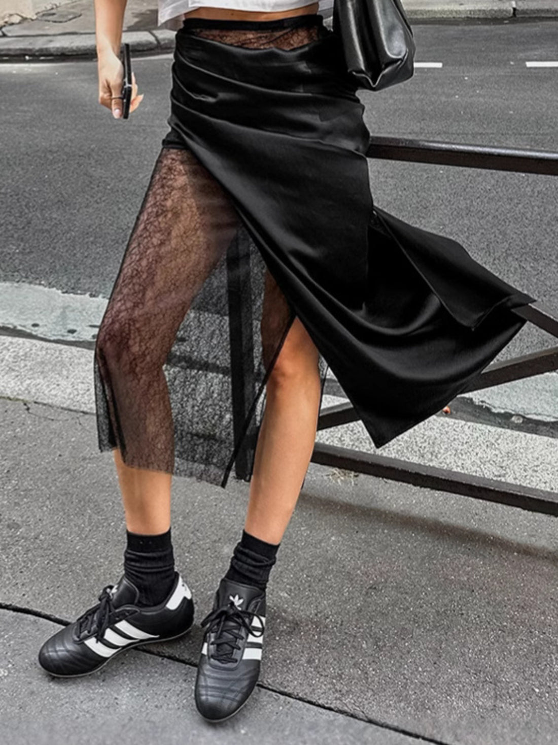 Black midi skirt with sheer lace panel and asymmetrical hem.