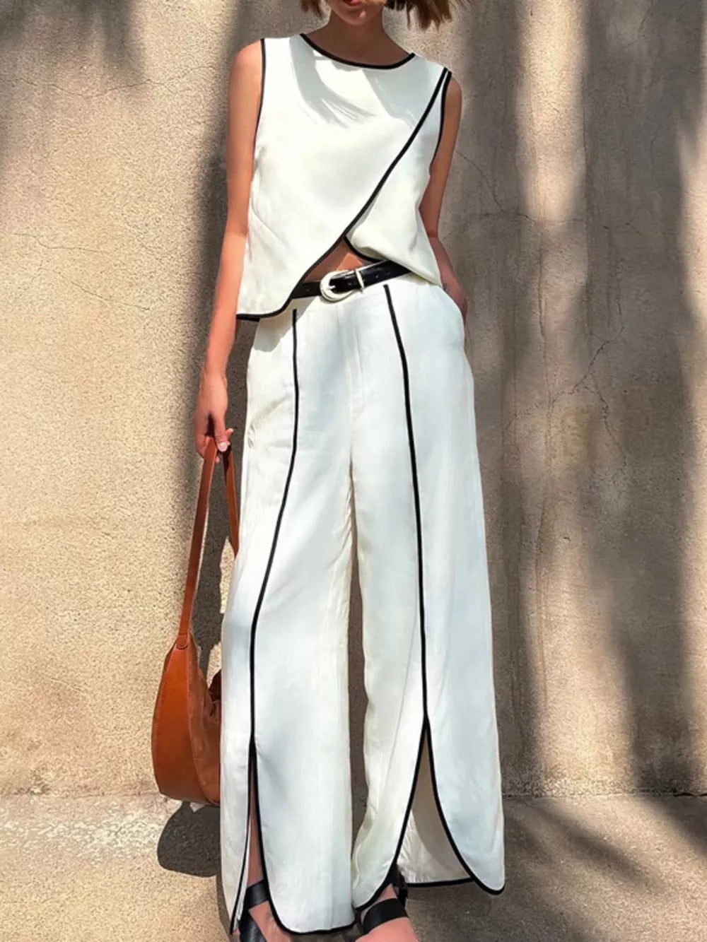 White sleeveless top and wide-leg pants set with black trim and side slits.