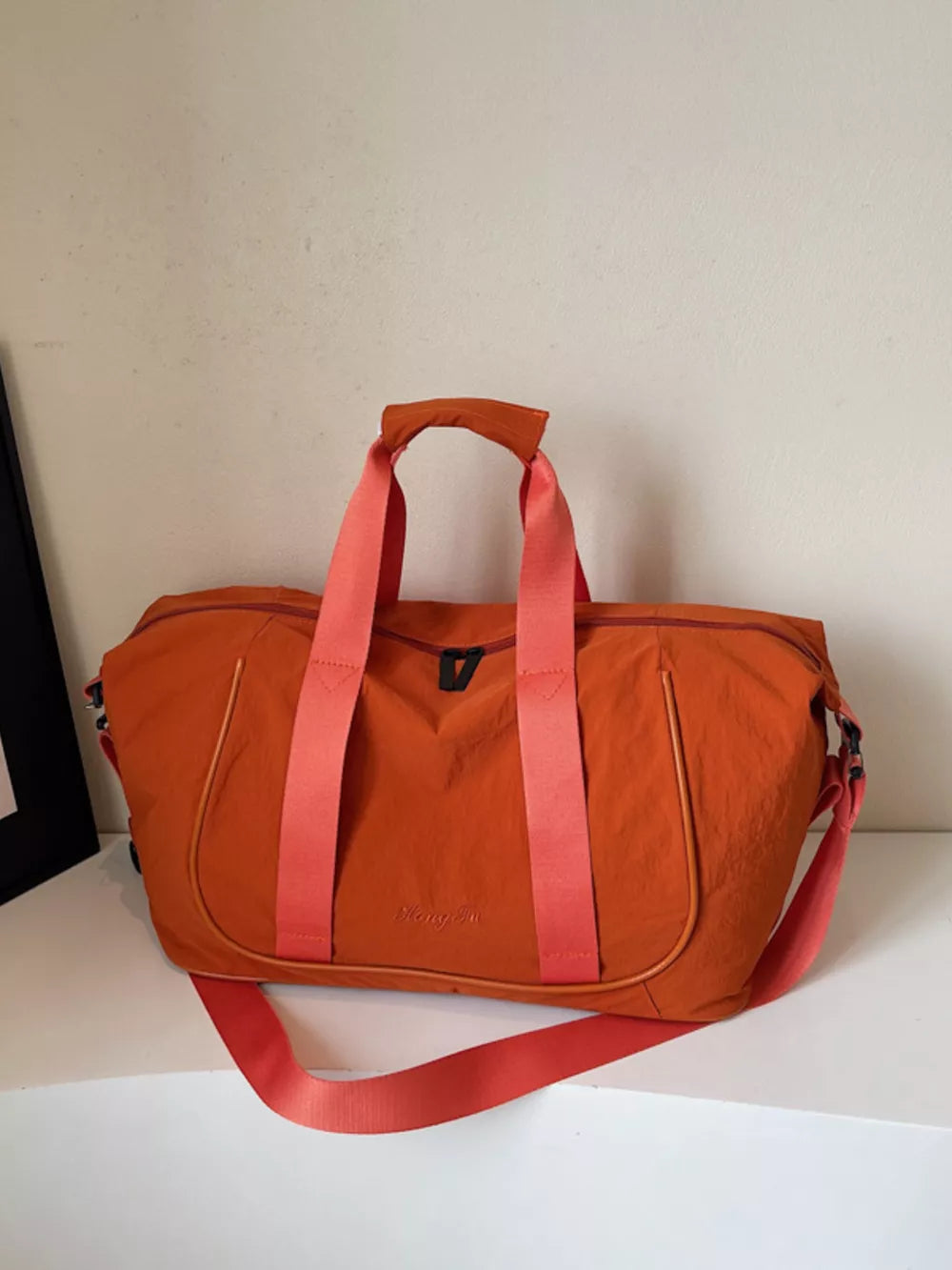 Orange lightweight Oxford cloth duffel bag with dual straps and adjustable shoulder strap.