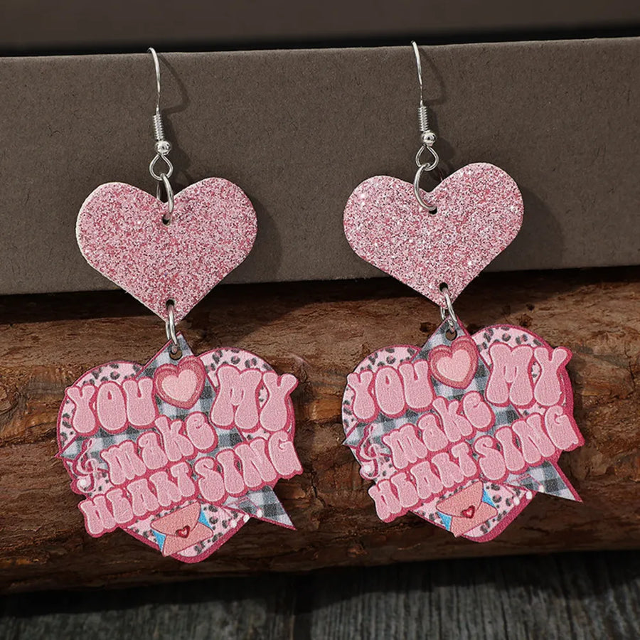 Blush pink glitter heart statement earrings with text that says "You make my heart sing