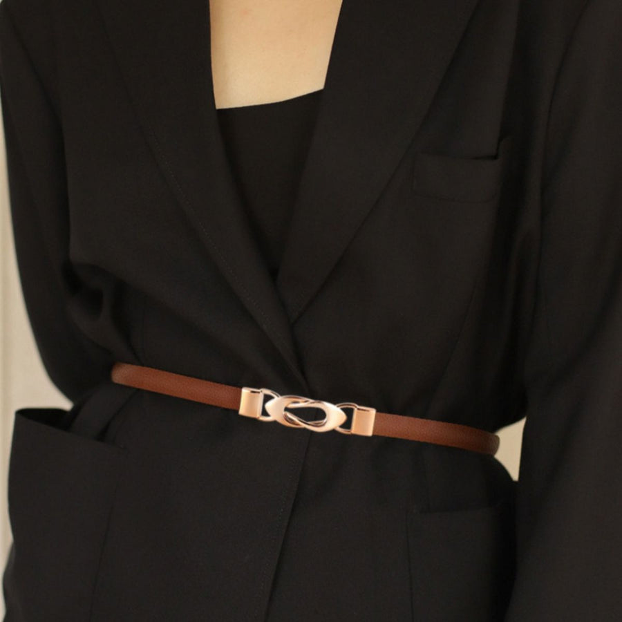 Brown leather belt with interlocking gold buckle cinching a black blazer.