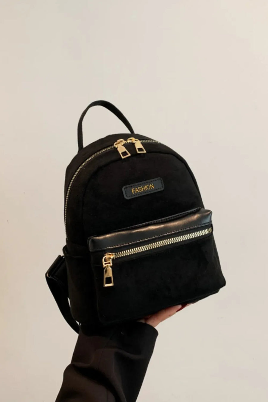 Black suede mini backpack with golden zips and "FASHION" detail