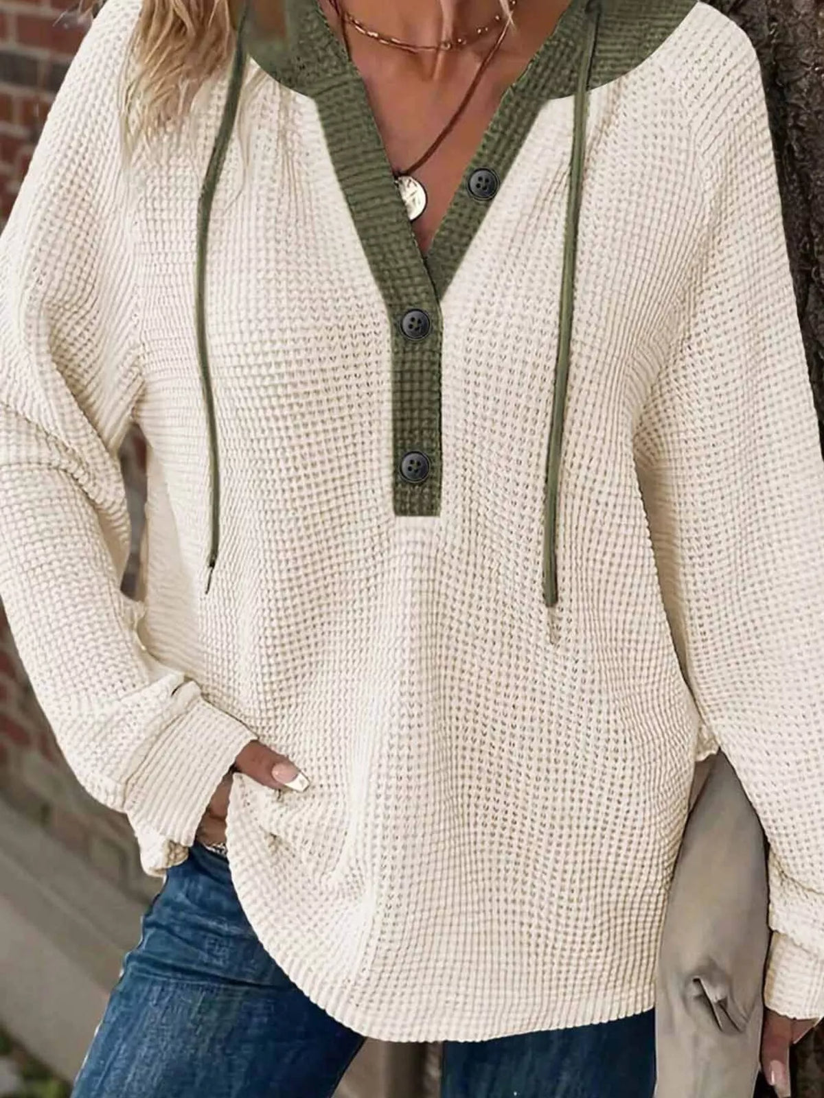 Beige waffle-knit hoodie with button detail and contrast green hood and placket.