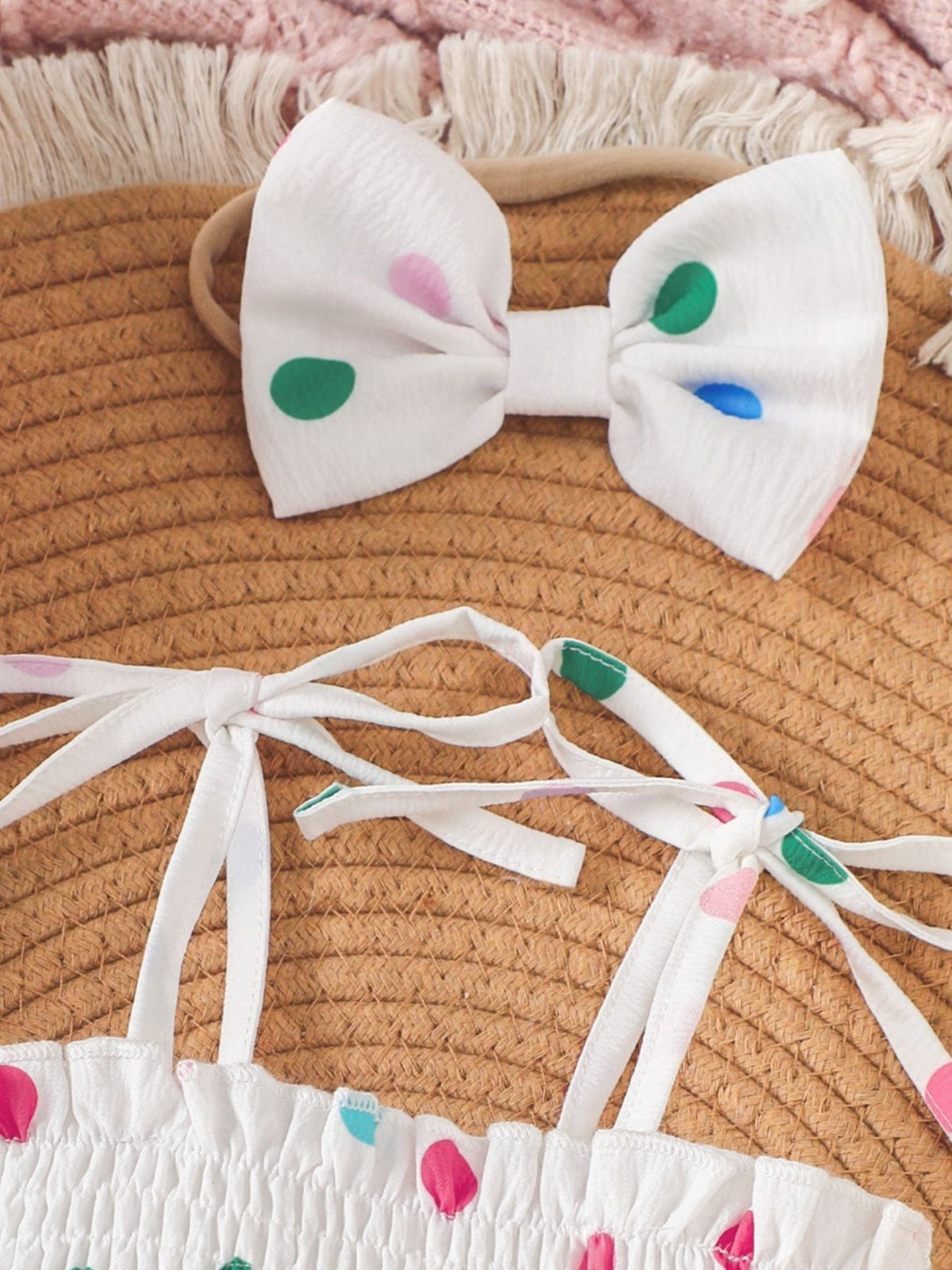 White smocked bodysuit dress set with polka dots and matching bow headband.