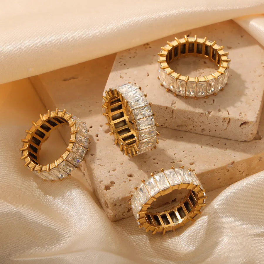 Gold baguette eternity band rings with clear rectangular stones.