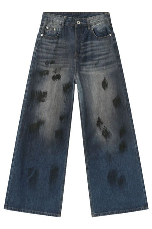 Oversized charcoal wash denim jeans with distressed black paint splatters and wide leg.