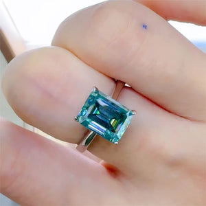 Emerald cut teal moissanite ring in silver with a bright gemstone.