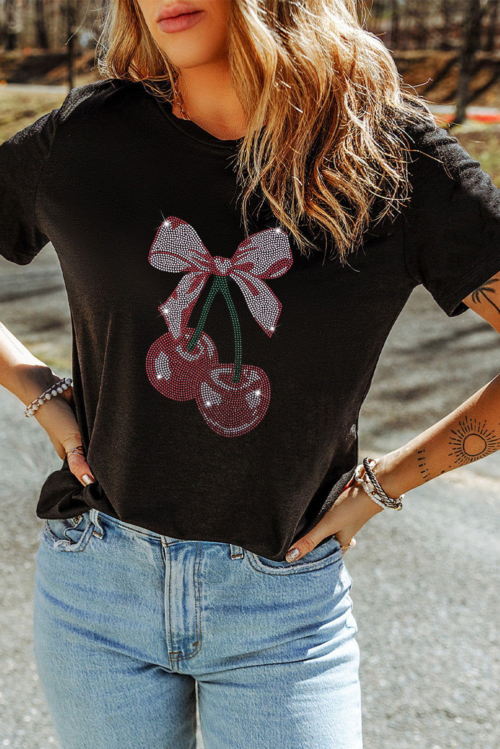 Black t-shirt with rhinestone cherry bow graphic detail.