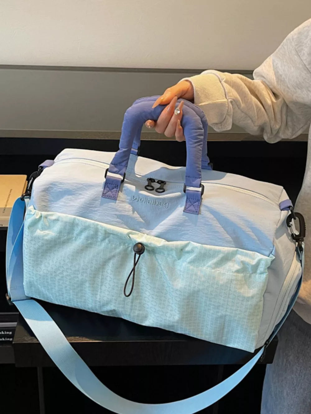 Chic two-tone nylon travel bag with aqua patterned front pocket and detachable strap.