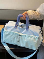 Chic two-tone nylon travel bag with aqua patterned front pocket and detachable strap.