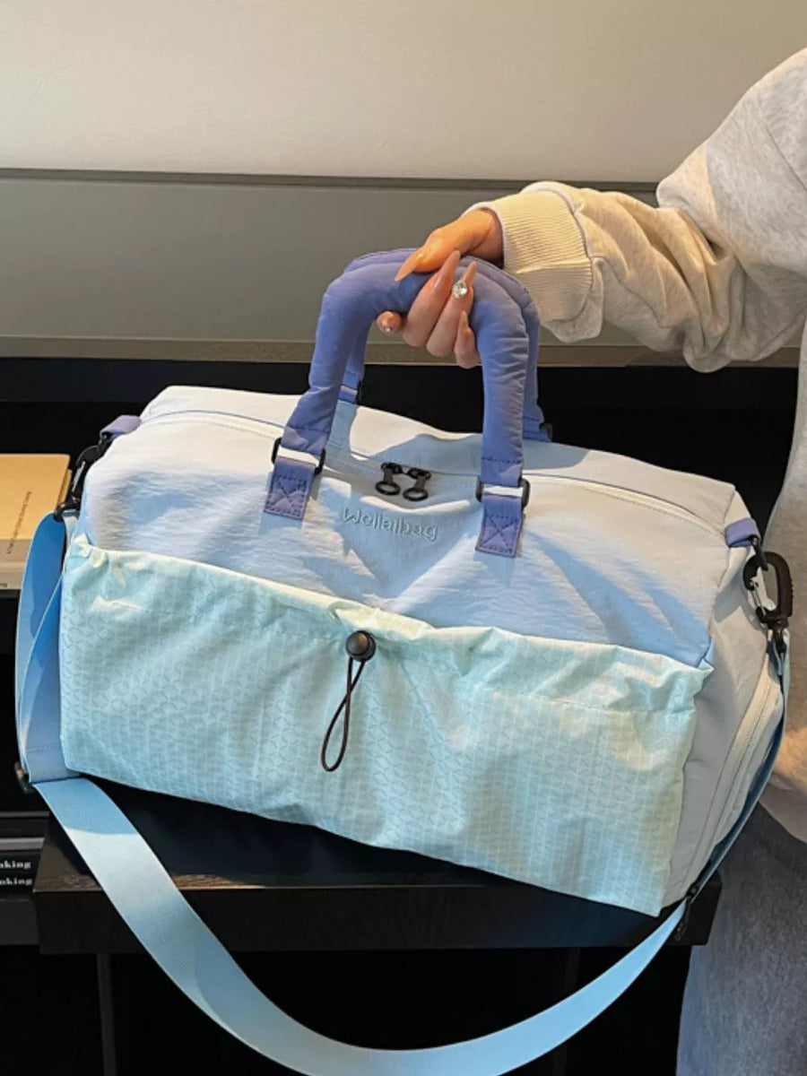 Chic two-tone nylon travel bag with aqua patterned front pocket and detachable strap.