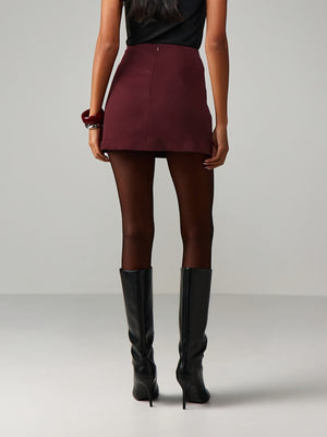 Burgundy high-waisted mini skirt with tie-side detail, styled with black tights and boots.