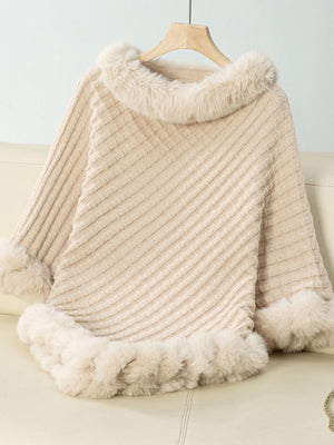 Beige knit poncho with faux fur trim at neckline and hem.