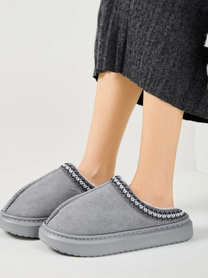 Gray shearling house slippers with embroidered trim and faux fur lining.