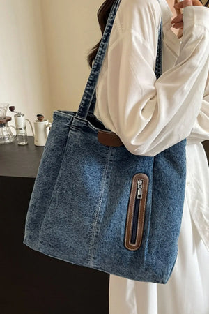 Denim shopper tote bag with leather trim and zippered pocket in medium blue wash.