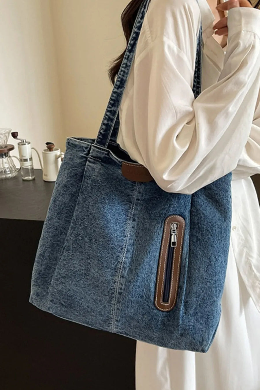 Denim shopper tote bag with leather trim and zippered pocket in medium blue wash.