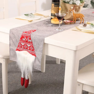 Gray table runner with a festive gnome accent featuring a red knit hat with reindeer and snowflakes.