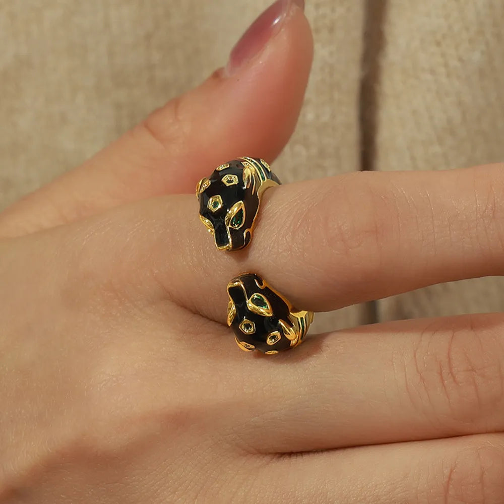 Gold panther head open ring with black enamel and green gem eyes.