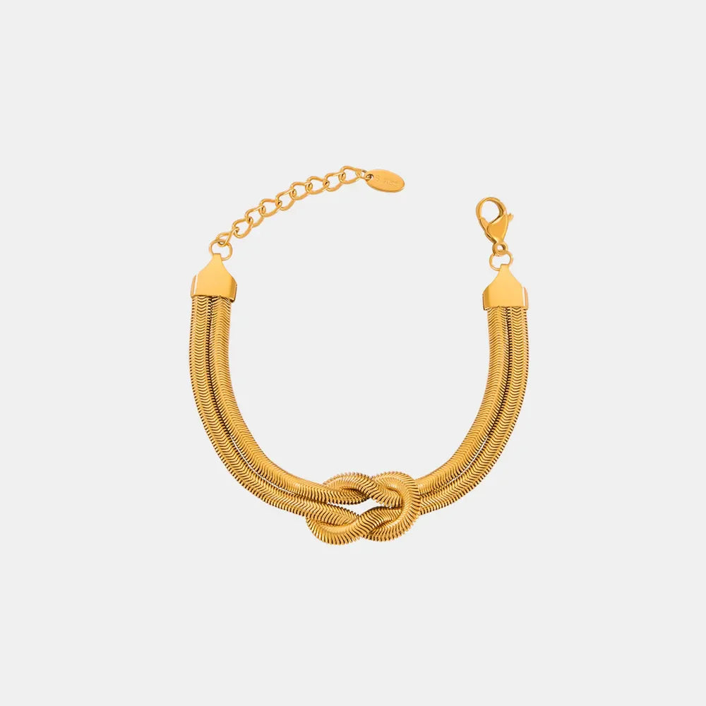 Gold serpent knot cuff bracelet with adjustable chain and clasp.