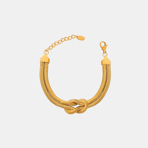 Gold serpent knot cuff bracelet with adjustable chain and clasp.
