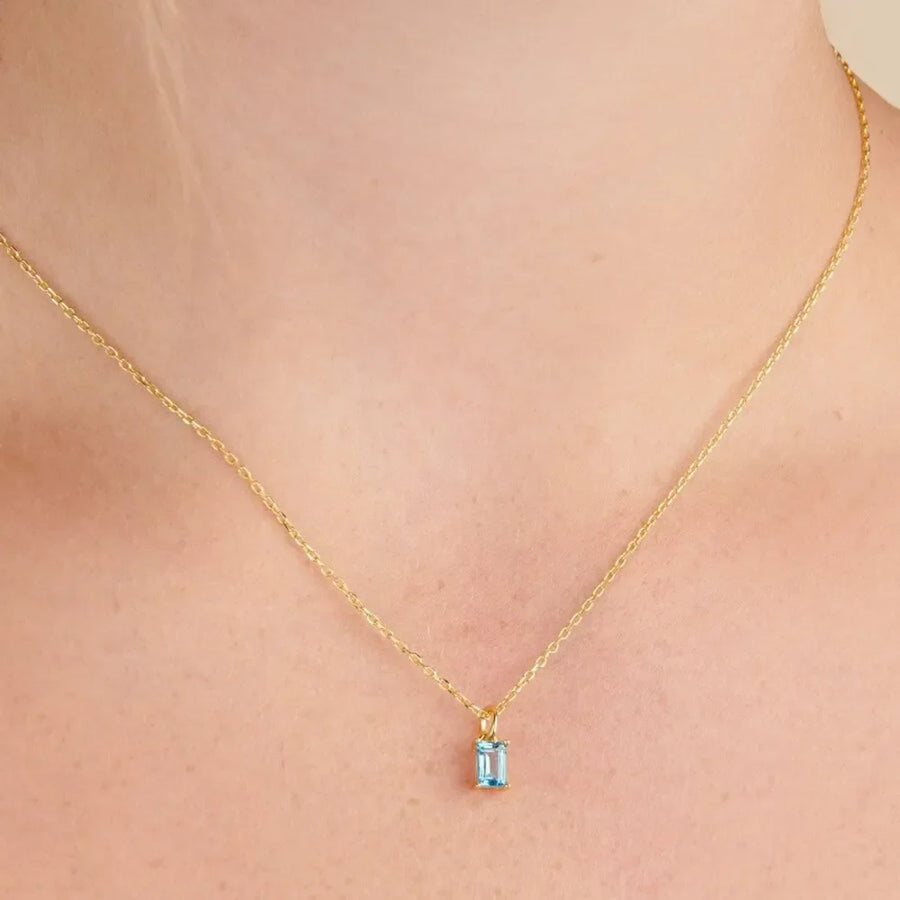18K gold necklace with a rectangular prism cut blue gemstone pendant.