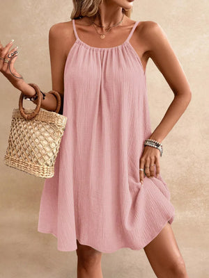 Pink spaghetti strap gauze dress with gathered neckline and A-line skirt.