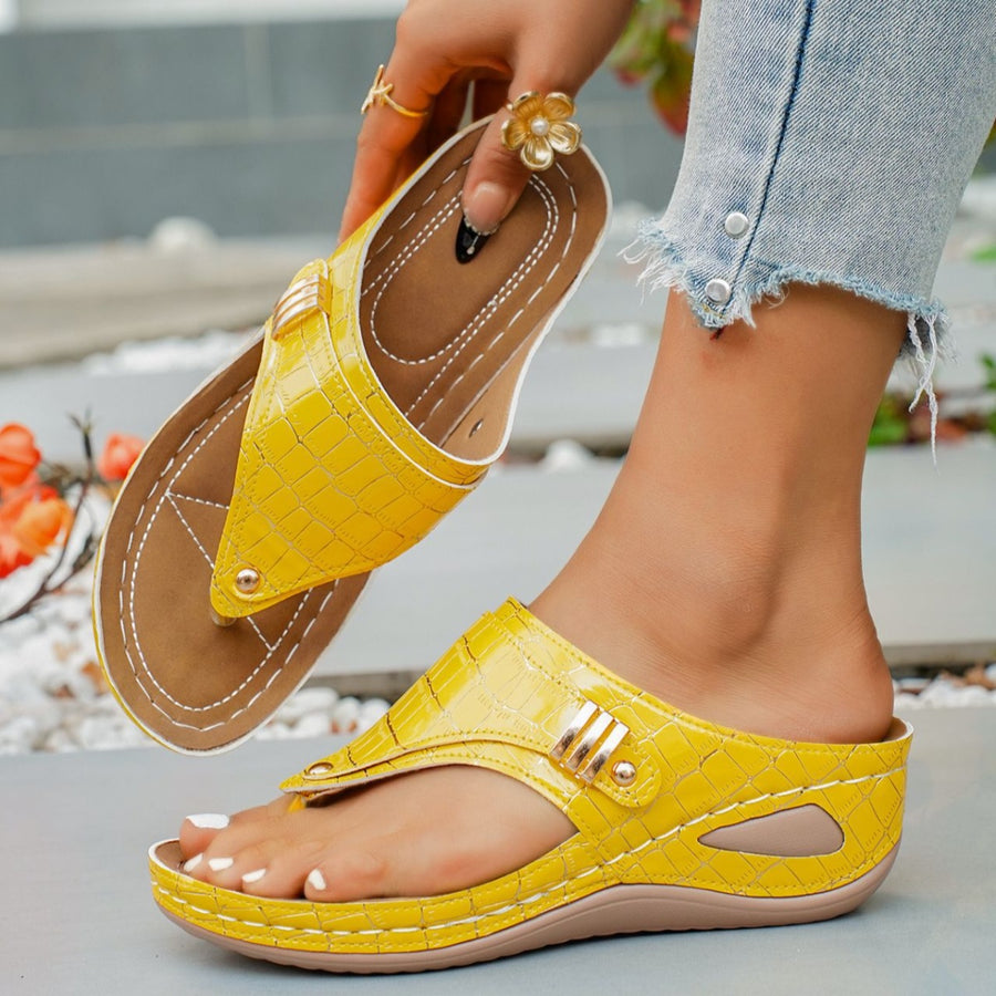 Yellow crocodile-embossed wedge thong sandals with gold buckle detail.
