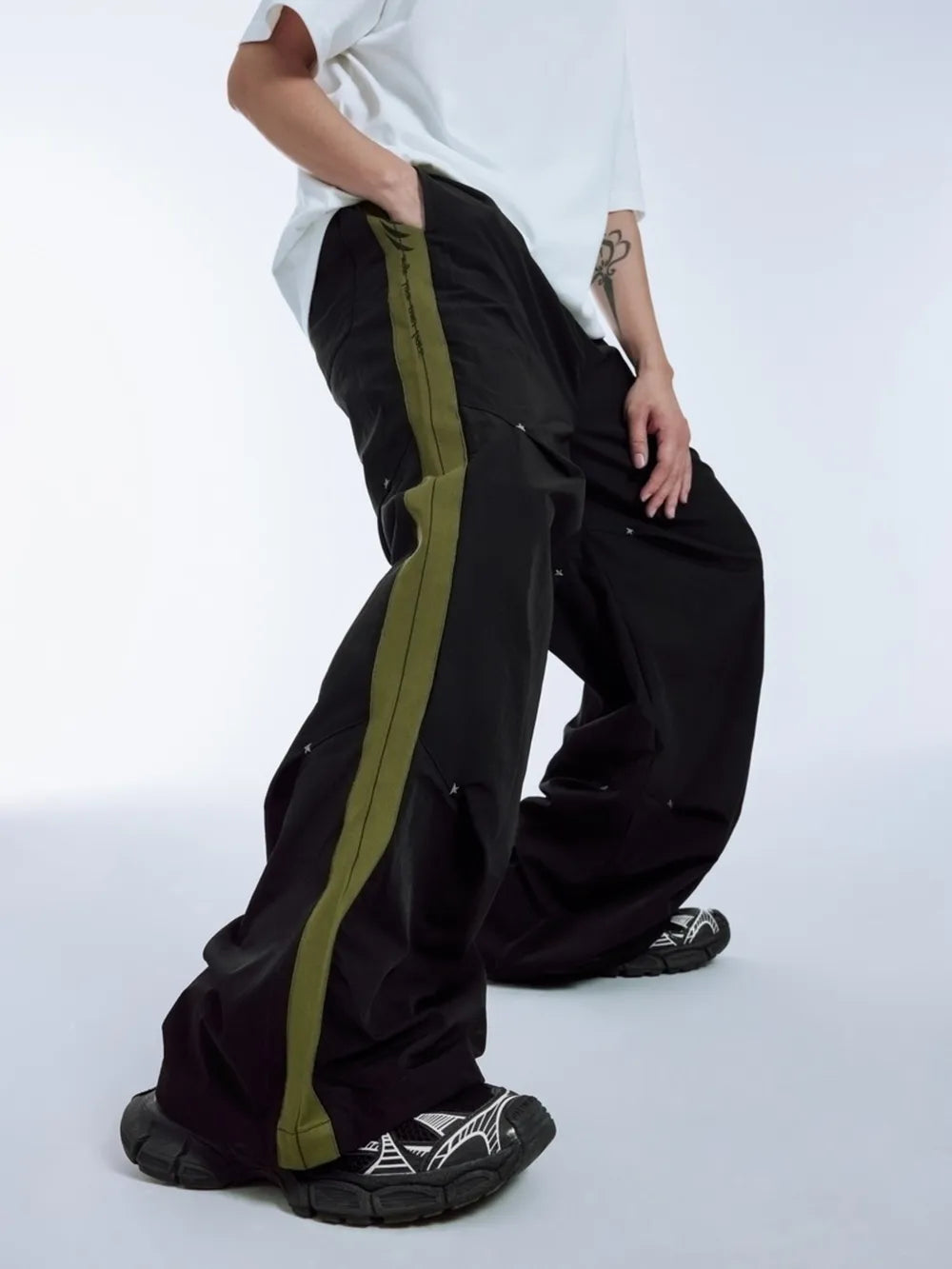 Black relaxed fit sweatpants with olive green side stripe and drawstring detail.