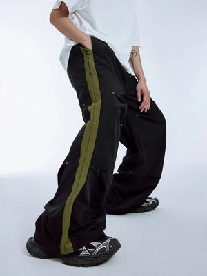 Black relaxed fit sweatpants with olive green side stripe and drawstring detail.