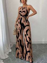 Elegant wide-leg jumpsuit in tan with abstract black print, halter neck, and tie waist.