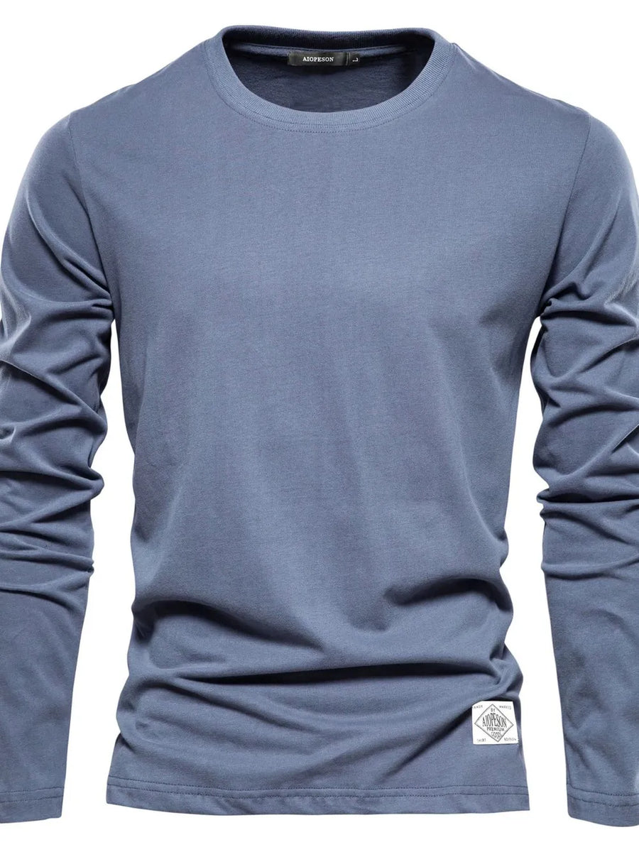 Dusty blue crew-neck long sleeve tee with textured fabric and a white patch detail.