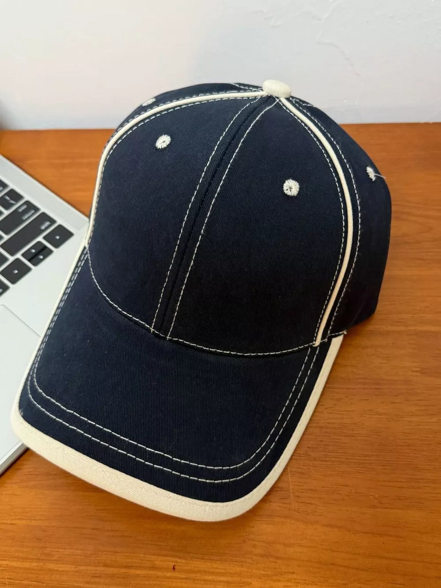 Navy blue cotton baseball cap with contrast stitching and cream white trim.