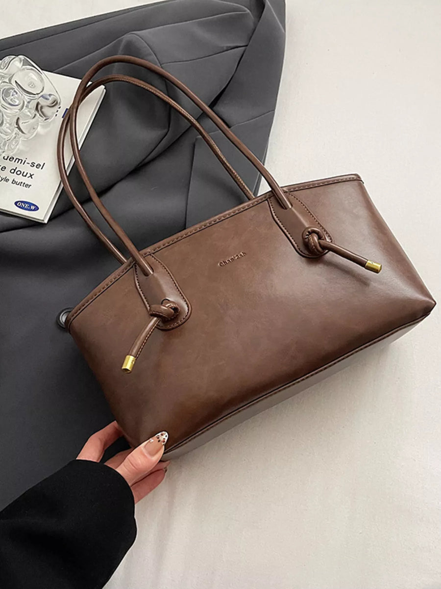 Brown leather shoulder bag with knotted strap details and gold hardware.