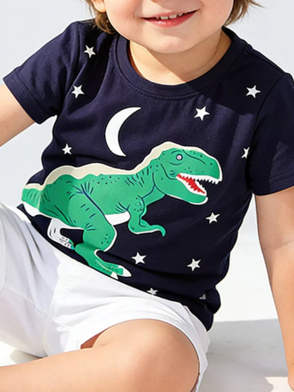 Navy cotton t-shirt with a green dinosaur, moon, and stars graphic for kids.