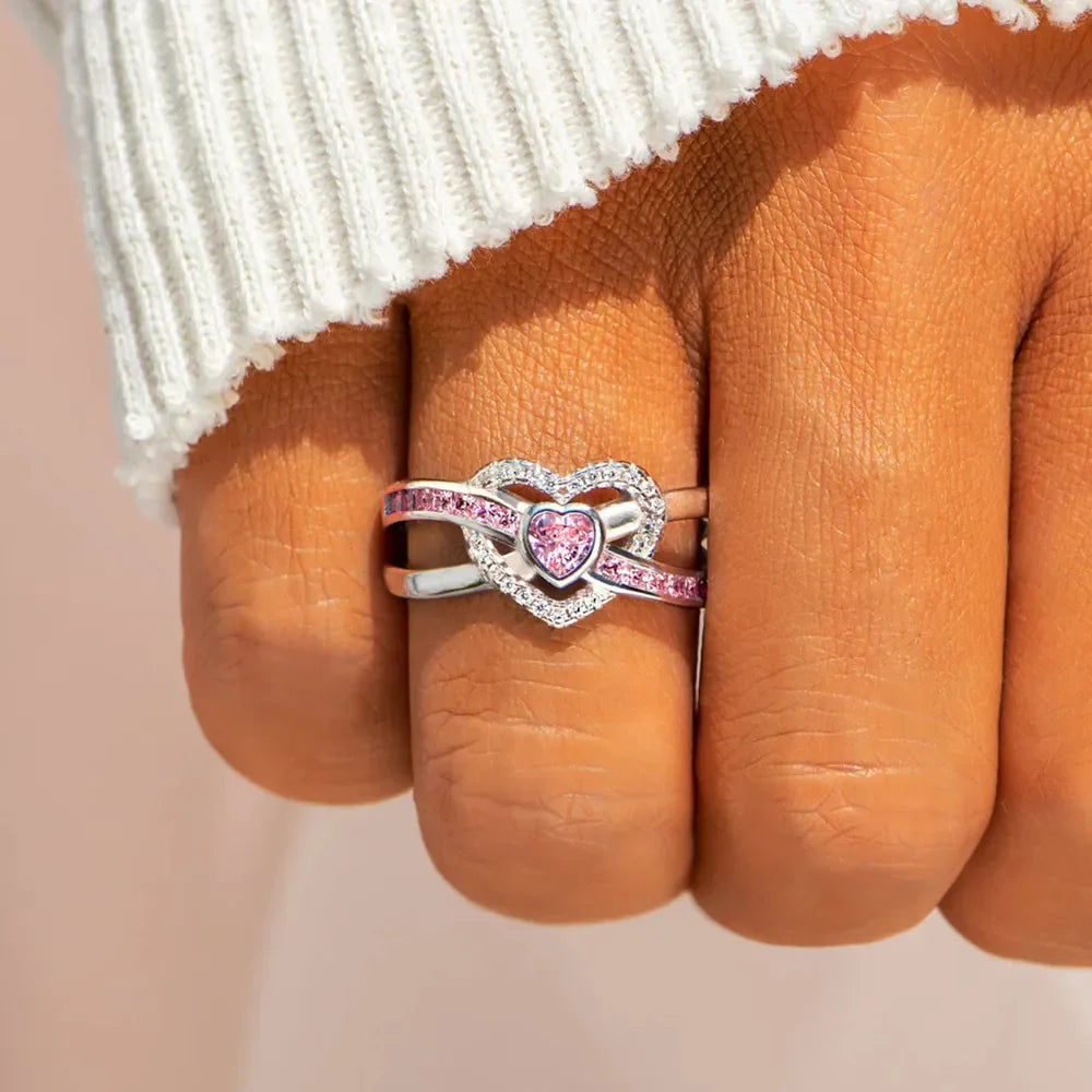 Silver ring with intertwined heart design featuring pink and clear zirconia stones.
