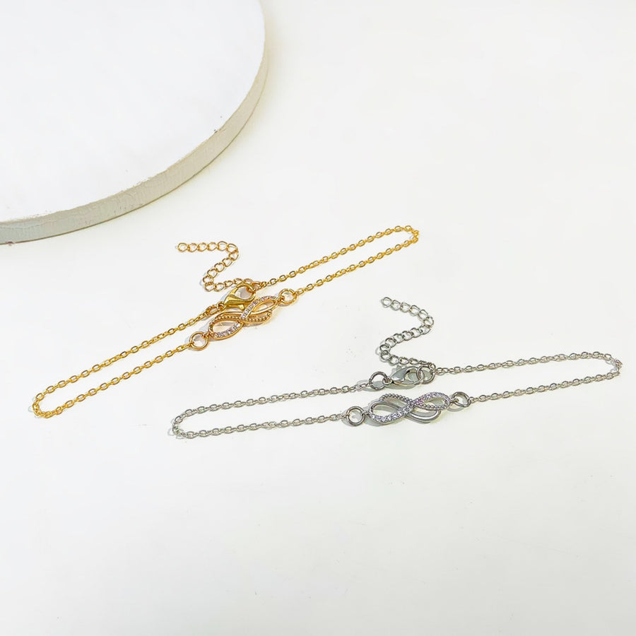 Gold and silver infinity knot charm bracelets with adjustable chains.