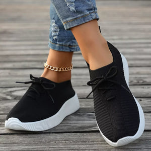 Black breathable lace-up sneakers with white mid sole and ribbed knit upper.