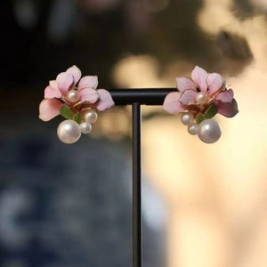 Floral pearl stud earrings in blush pink with dangling pearls and green leaf accents.
