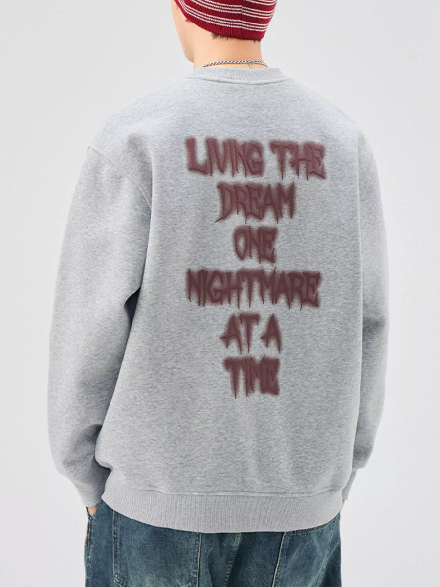 Oversized gray crew-neck sweatshirt with "Living the Dream One Nightmare at a Time" text graphic on back