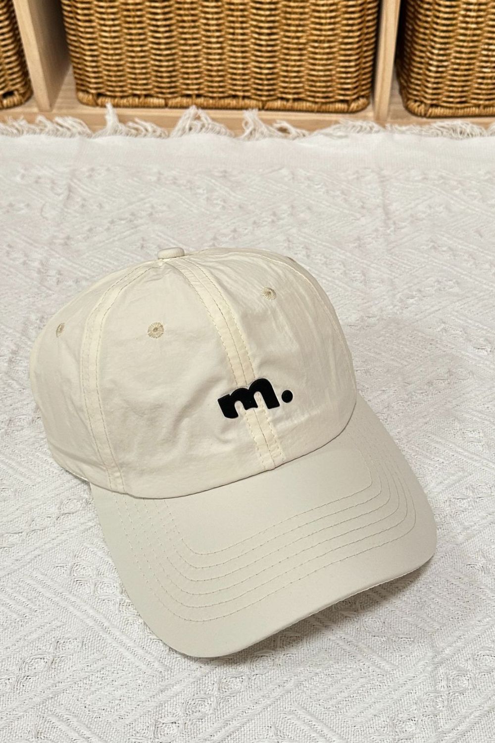Beige baseball cap with black m. logo