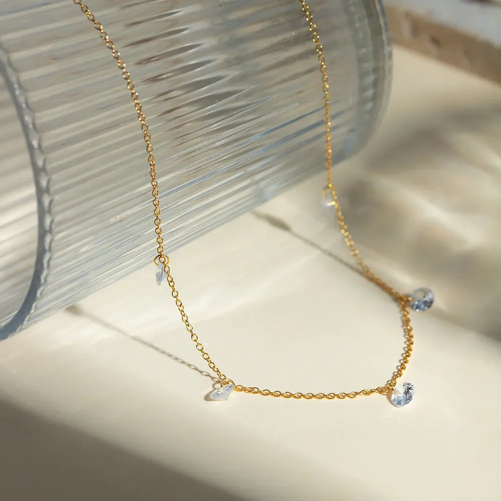 Gold dangling crystal station necklace with delicate chain and scattered clear crystals.