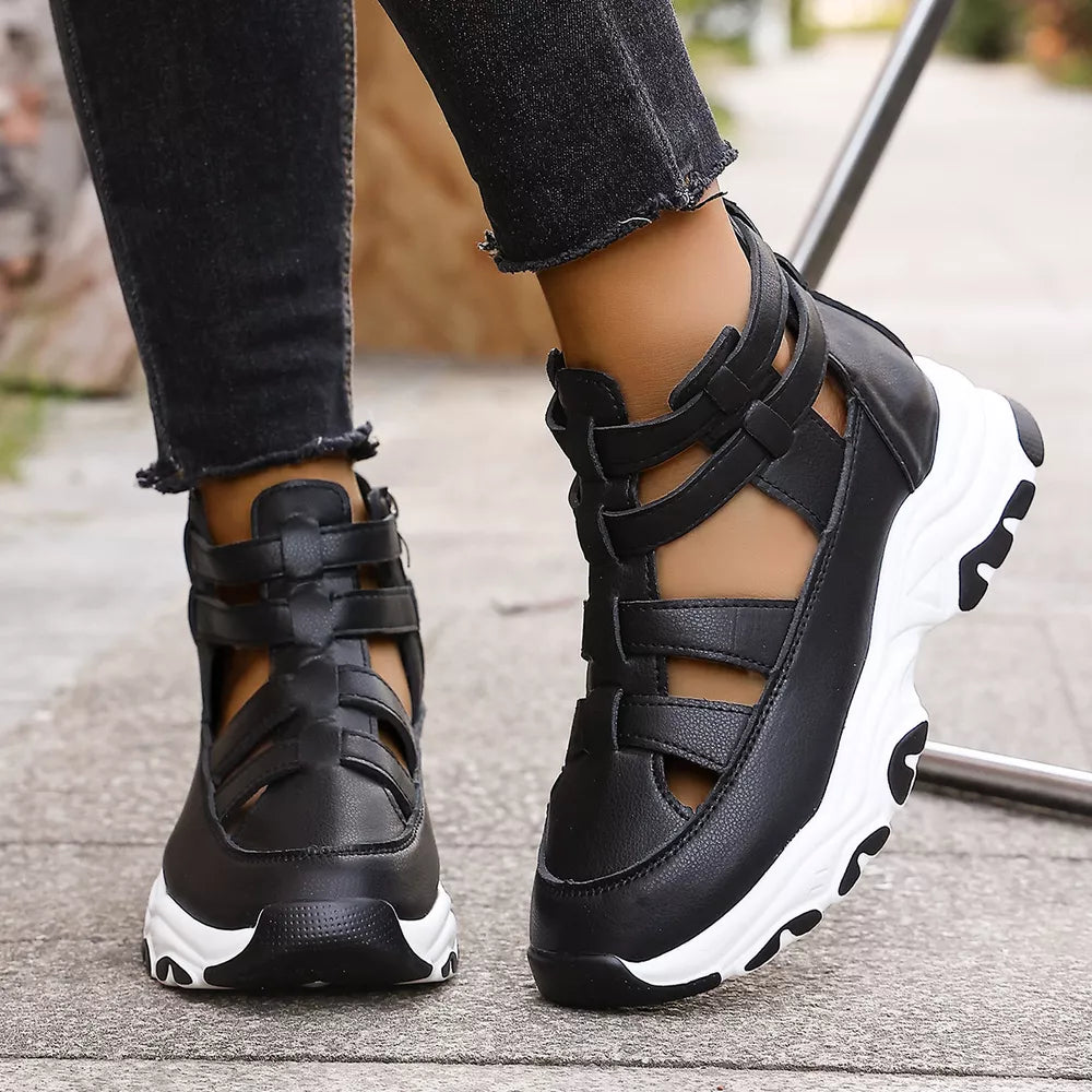 Black cutout platform sneakers with ankle straps and chunky white soles.