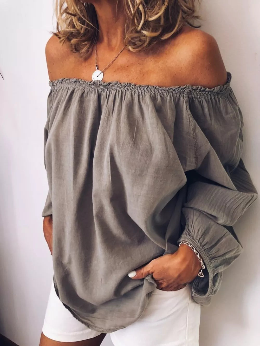 Gray off the shoulder shirt with gathered neckline and frill detail, long sleeves.