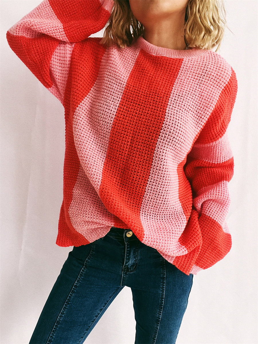 Vertical stripe waffle knit sweater in orange-red and pink with crewneck and long sleeves.