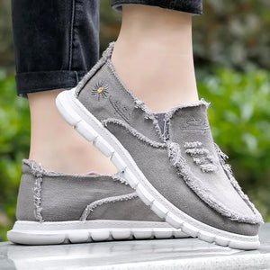 Gray canvas slip-on flats with raw edges and embroidered daisy detail.