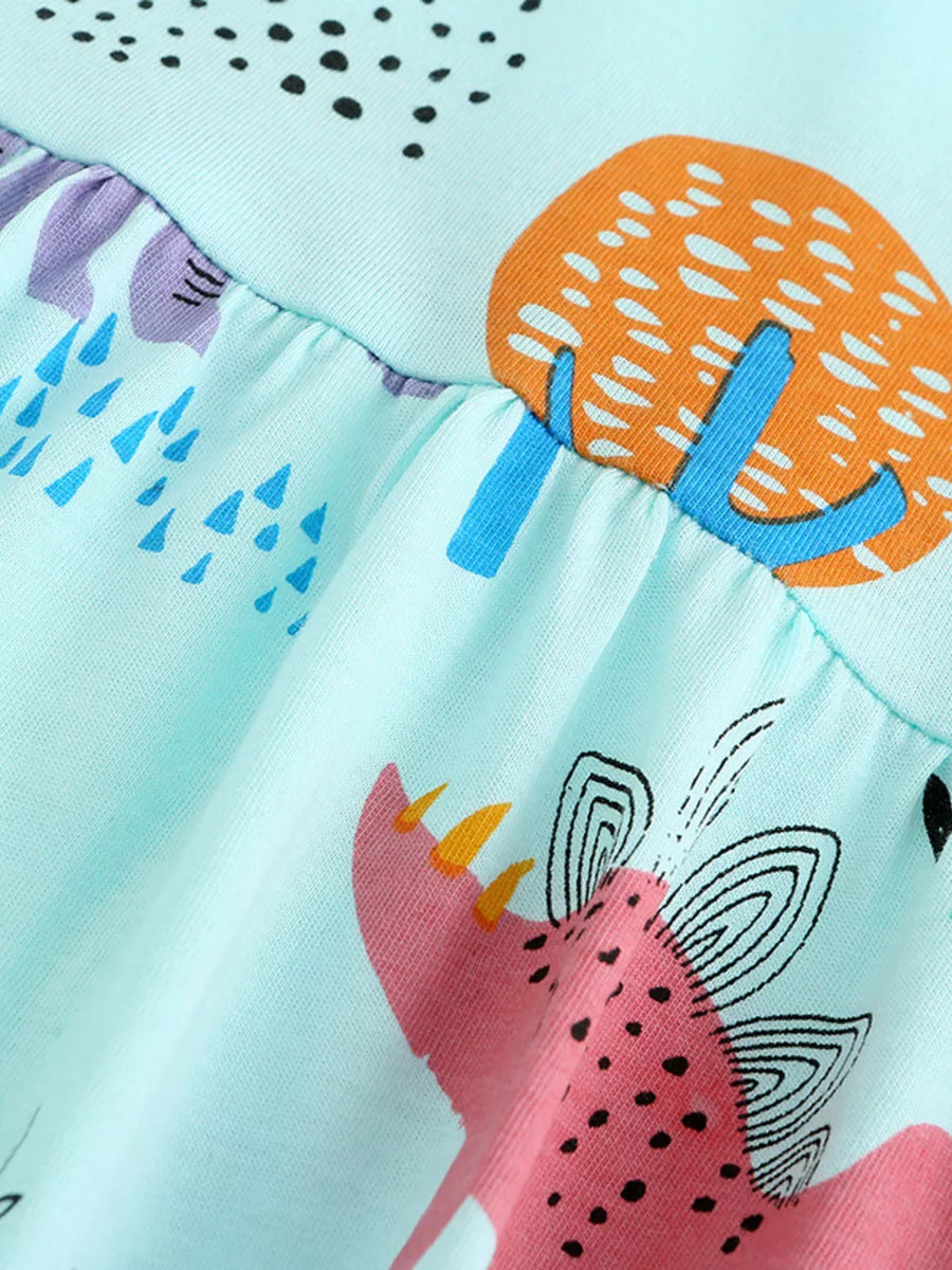 Light blue cotton dress with dinosaur and abstract print, ruffled hem.